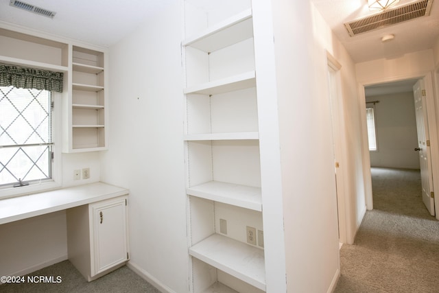 unfurnished office featuring light carpet, visible vents, and built in desk