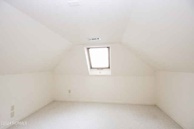 additional living space featuring light carpet, baseboards, visible vents, and vaulted ceiling