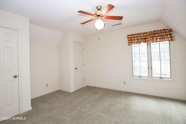 interior space with carpet floors, visible vents, vaulted ceiling, ceiling fan, and baseboards