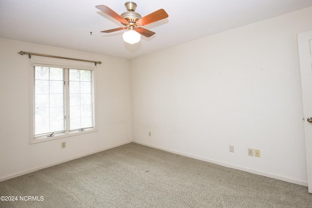 carpeted spare room featuring ceiling fan and baseboards