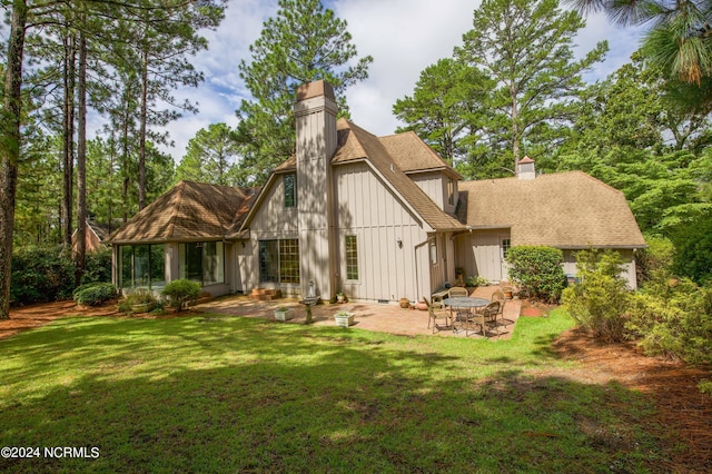 rear view of house with a yard, a chimney, and a patio area