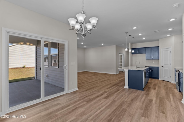 kitchen with pendant lighting, an inviting chandelier, light hardwood / wood-style flooring, blue cabinetry, and an island with sink