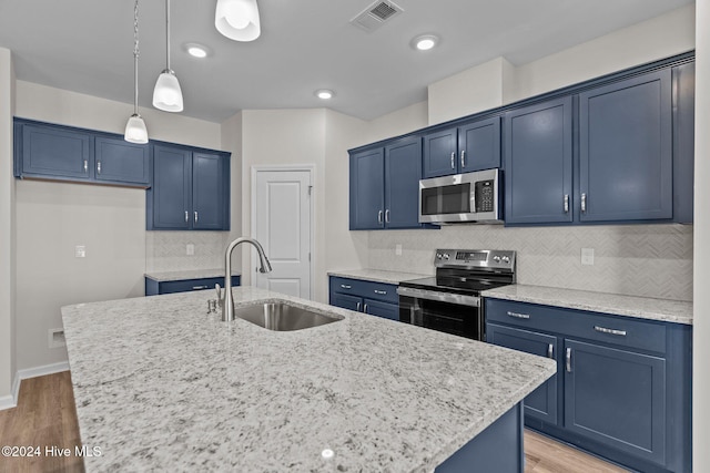 kitchen featuring a center island with sink, sink, appliances with stainless steel finishes, and hardwood / wood-style floors