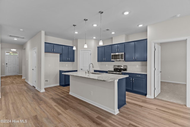 kitchen featuring appliances with stainless steel finishes, light stone counters, a kitchen island with sink, sink, and light hardwood / wood-style floors