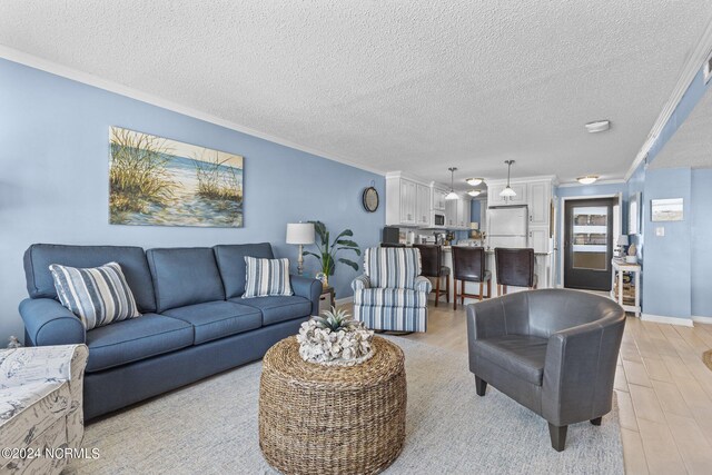 living room featuring a textured ceiling, light hardwood / wood-style flooring, and ornamental molding