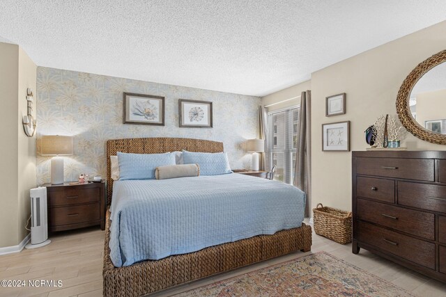 bedroom with a textured ceiling and light hardwood / wood-style floors