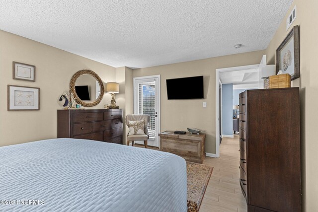 bedroom featuring light hardwood / wood-style floors and a textured ceiling