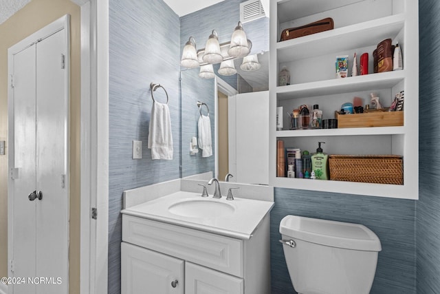 bathroom featuring vanity, built in shelves, and toilet