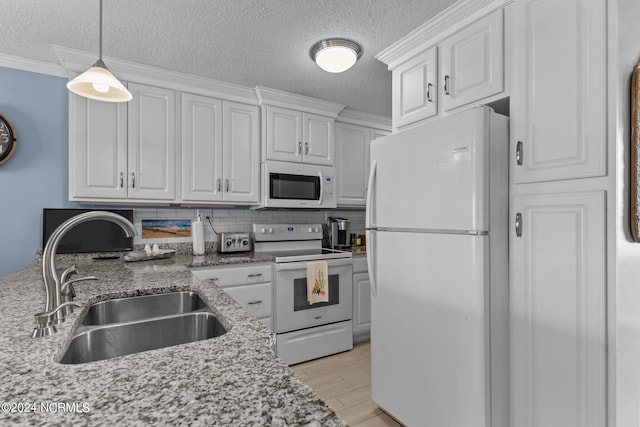 kitchen featuring white appliances, a textured ceiling, backsplash, light stone counters, and sink