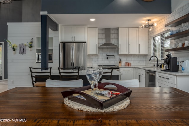 kitchen with white cabinets, appliances with stainless steel finishes, sink, wall chimney exhaust hood, and decorative backsplash