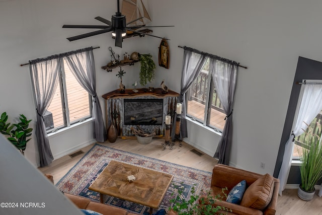 living room with ceiling fan, a fireplace, and light hardwood / wood-style flooring