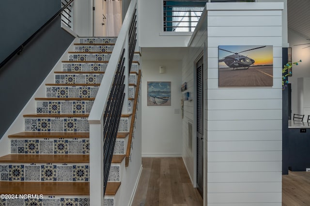 stairs with a towering ceiling and hardwood / wood-style floors