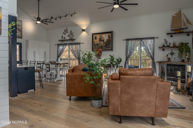 living room featuring high vaulted ceiling, rail lighting, ceiling fan, and light hardwood / wood-style floors