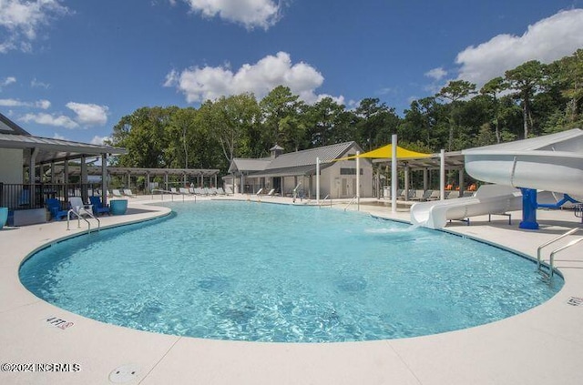 view of swimming pool with a patio and a water slide