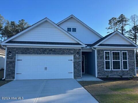 view of front of home with a garage, stone siding, and driveway