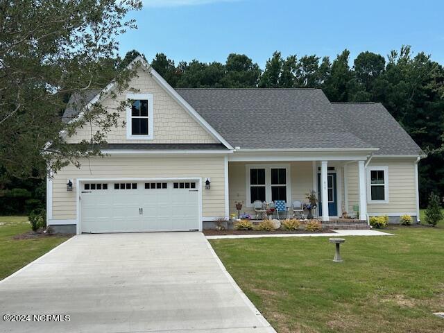 view of front of property featuring a garage, a front yard, and a porch