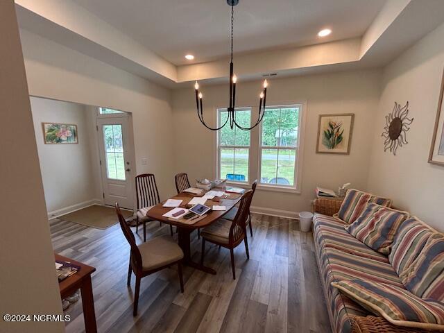 dining space with dark hardwood / wood-style floors, a wealth of natural light, a notable chandelier, and a tray ceiling