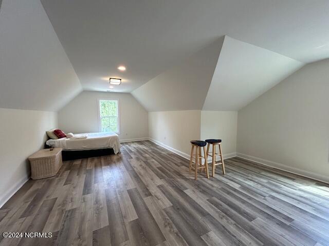 additional living space with vaulted ceiling and dark hardwood / wood-style floors