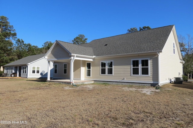 rear view of property with central AC unit, a patio area, and a lawn