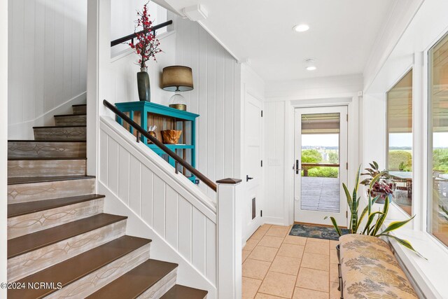 entrance foyer with light tile patterned floors and ornamental molding