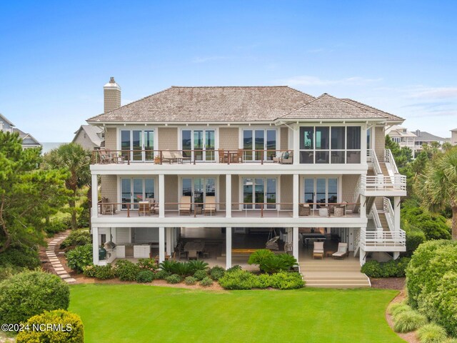 back of property with a balcony and a lawn