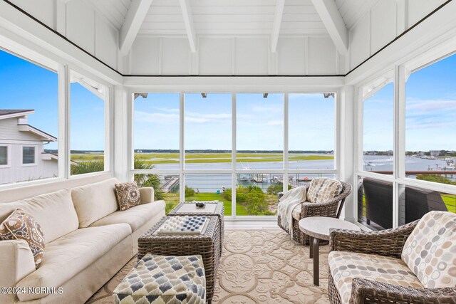 sunroom / solarium featuring a water view and vaulted ceiling with beams