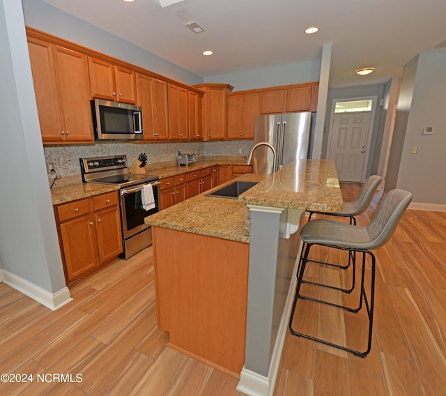 kitchen with tasteful backsplash, stainless steel appliances, sink, a breakfast bar area, and a center island with sink