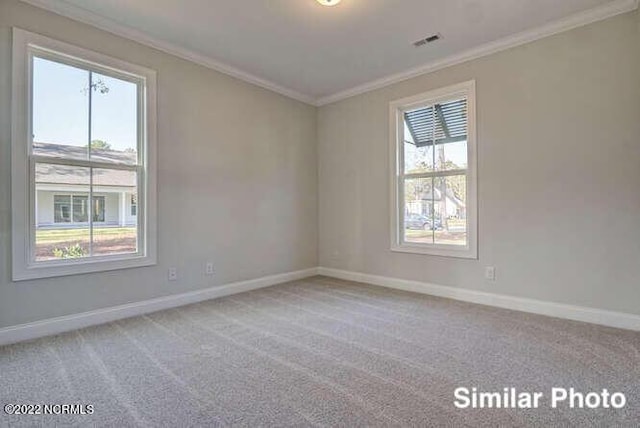 empty room with carpet, visible vents, baseboards, and ornamental molding