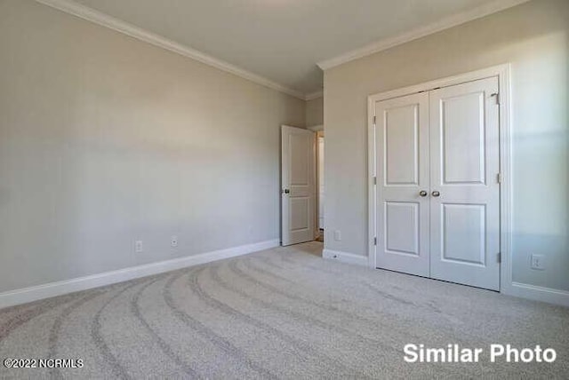 unfurnished bedroom with carpet floors, a closet, crown molding, and baseboards