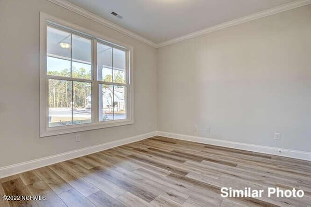 unfurnished room featuring baseboards, wood finished floors, visible vents, and crown molding