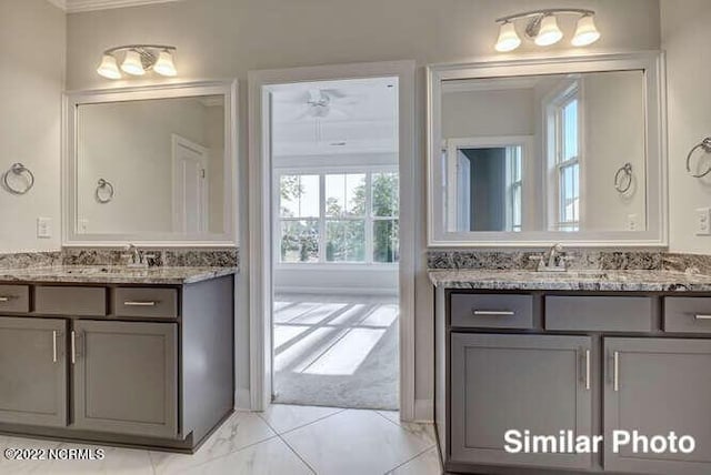 bathroom with marble finish floor, two vanities, and a sink