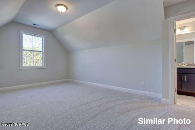 bonus room with vaulted ceiling, light carpet, and baseboards