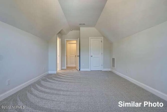 bonus room featuring lofted ceiling, carpet flooring, and baseboards