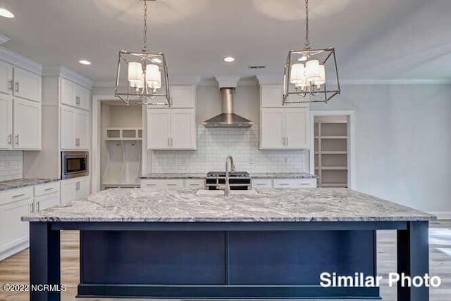 kitchen featuring wall chimney exhaust hood, appliances with stainless steel finishes, white cabinets, and crown molding