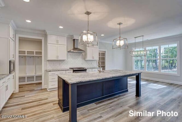 kitchen featuring tasteful backsplash, white cabinets, ornamental molding, stainless steel range with electric cooktop, and wall chimney range hood