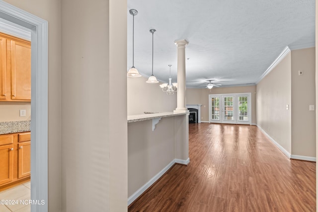 interior space with light hardwood / wood-style floors, a textured ceiling, ornamental molding, and an inviting chandelier