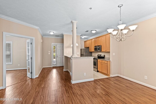 kitchen with appliances with stainless steel finishes, light wood-type flooring, ornate columns, light brown cabinetry, and a notable chandelier