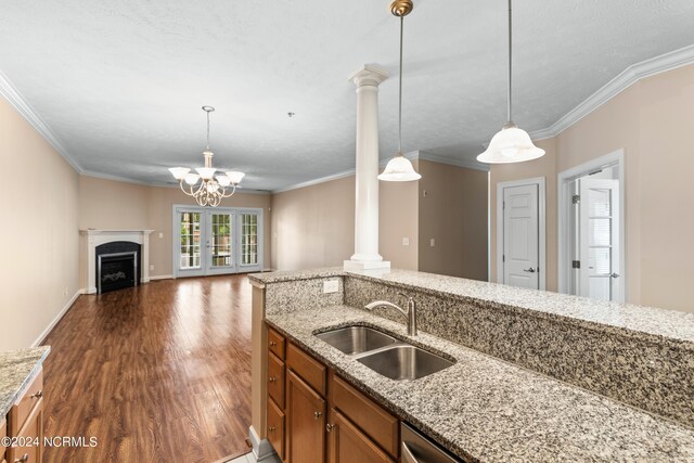 kitchen featuring decorative columns, sink, dark wood-type flooring, and ornamental molding