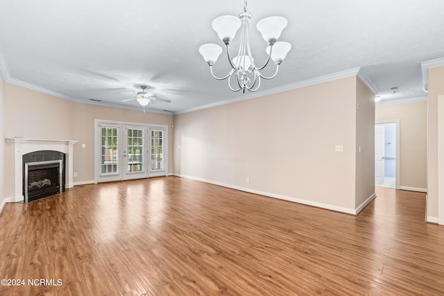 unfurnished living room with hardwood / wood-style flooring, a tiled fireplace, ceiling fan with notable chandelier, and ornamental molding