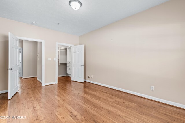 unfurnished bedroom with a closet, light hardwood / wood-style flooring, and a spacious closet