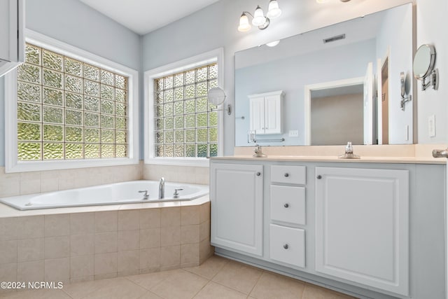 bathroom featuring a relaxing tiled tub, tile patterned flooring, and dual vanity