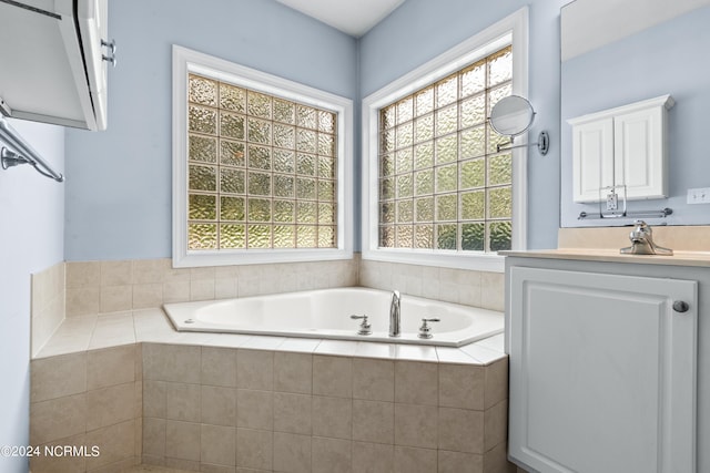 bathroom with tiled tub and vanity