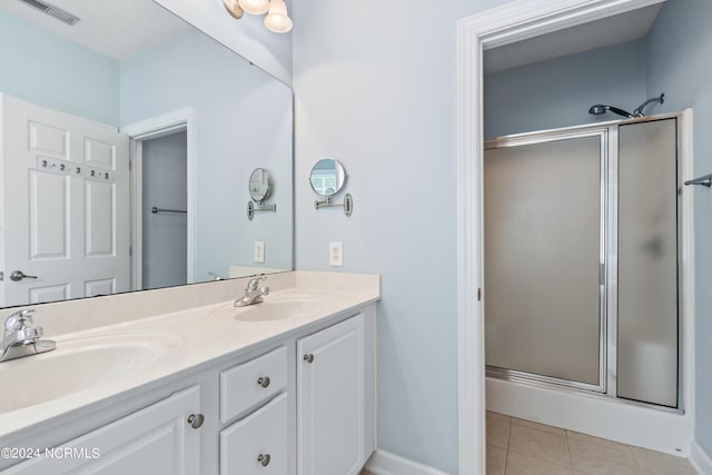 bathroom with a shower with door, double vanity, and tile patterned flooring