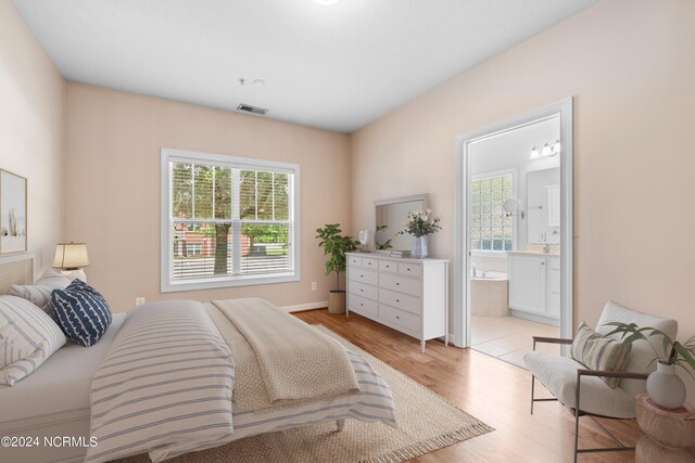 bedroom with light hardwood / wood-style flooring, multiple windows, and connected bathroom