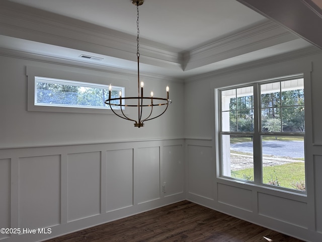 unfurnished dining area with a raised ceiling, a chandelier, ornamental molding, and dark wood-type flooring