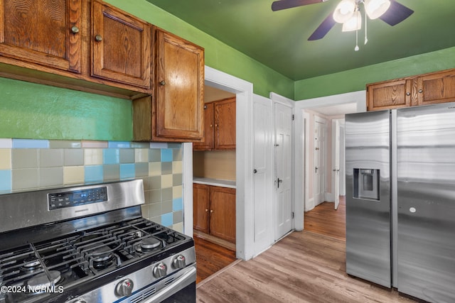 kitchen with appliances with stainless steel finishes, ceiling fan, light hardwood / wood-style flooring, and decorative backsplash