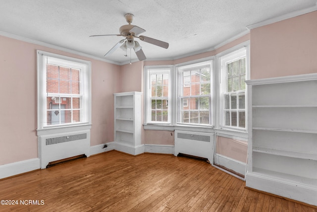 empty room with light hardwood / wood-style floors, crown molding, radiator, and a textured ceiling