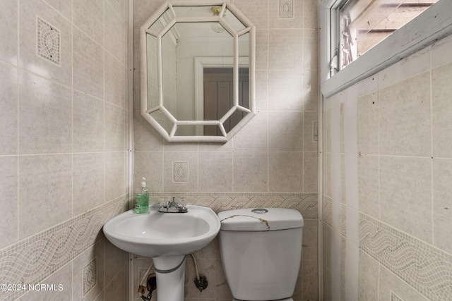 bathroom featuring tile walls and toilet