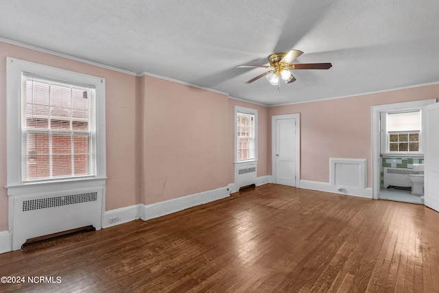 empty room with ornamental molding, dark hardwood / wood-style floors, a textured ceiling, and radiator heating unit