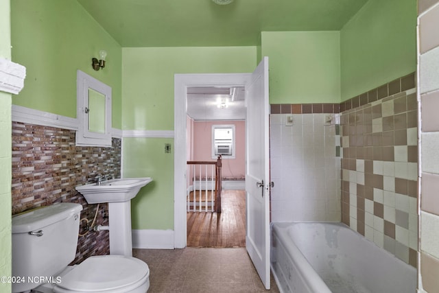 bathroom with a washtub, tile patterned floors, and toilet